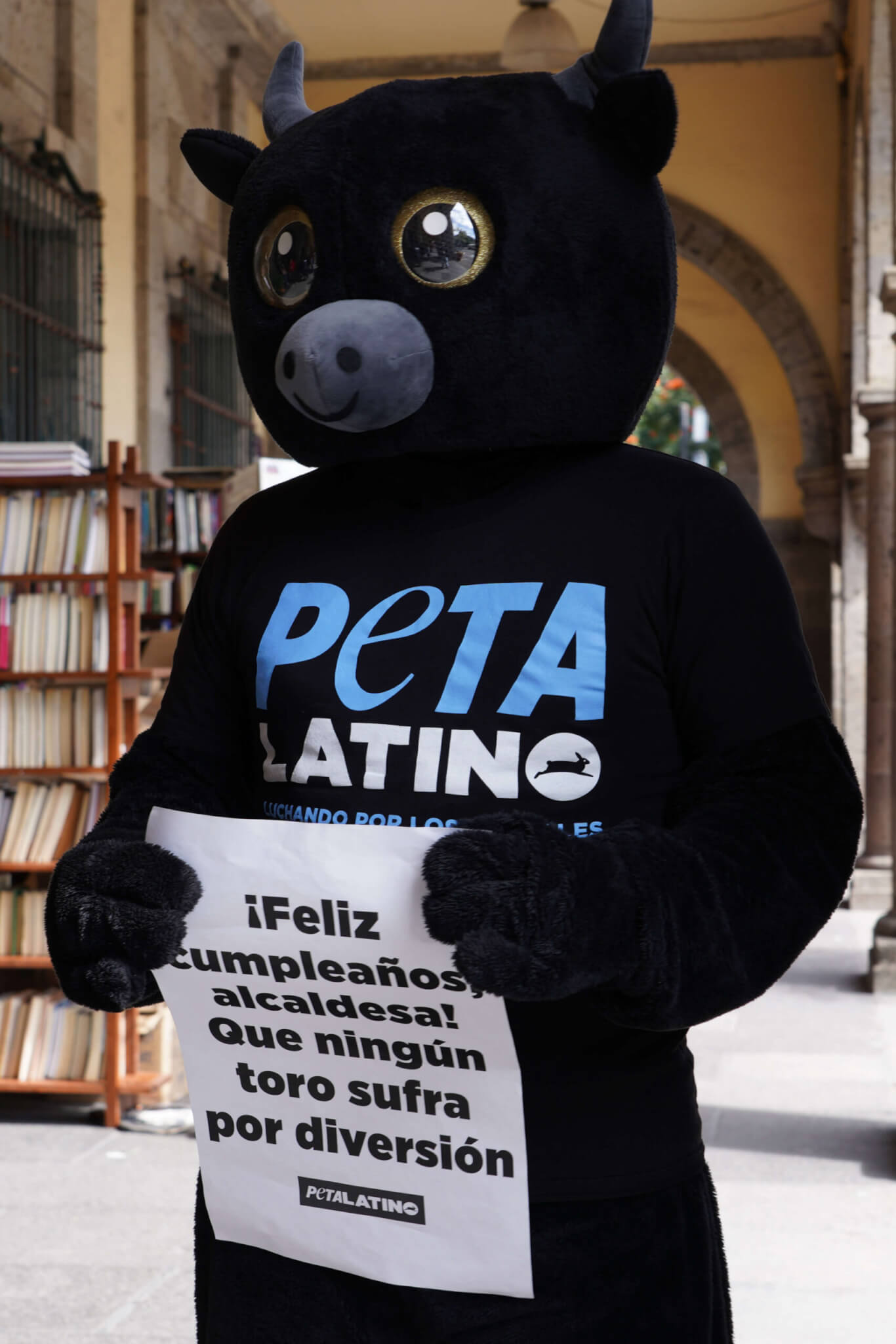 PETA Latino activist in a black bull costume holding a sign